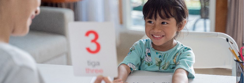 Niño feliz estudiando inglés en casa con un familiar
